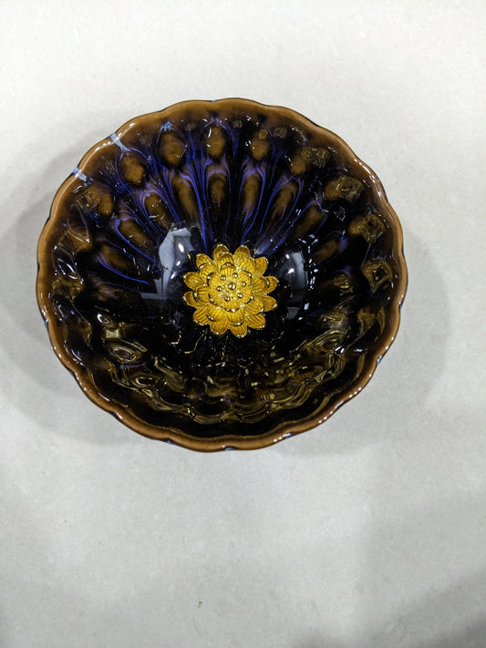 Angled close-up of the glossy ceramic interior and textured golden lotus flower in the center