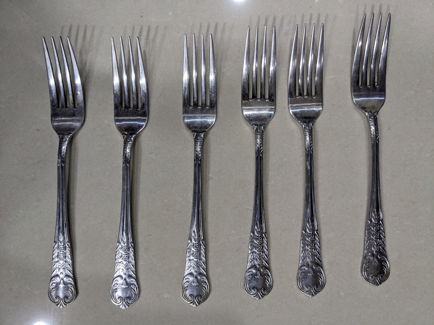 Set of 6 matching vintage silver-plated dinner forks lined up on a clean neutral background