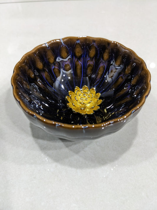 Top-down view of a vintage glazed ceramic bowl with a golden lotus flower centerpiece