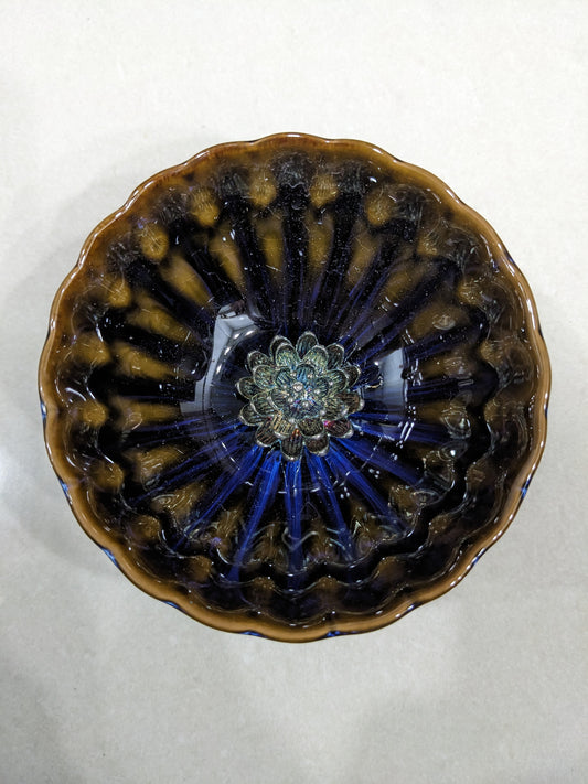 Top-down view of a vintage glazed ceramic bowl featuring an iridescent metallic lotus flower center