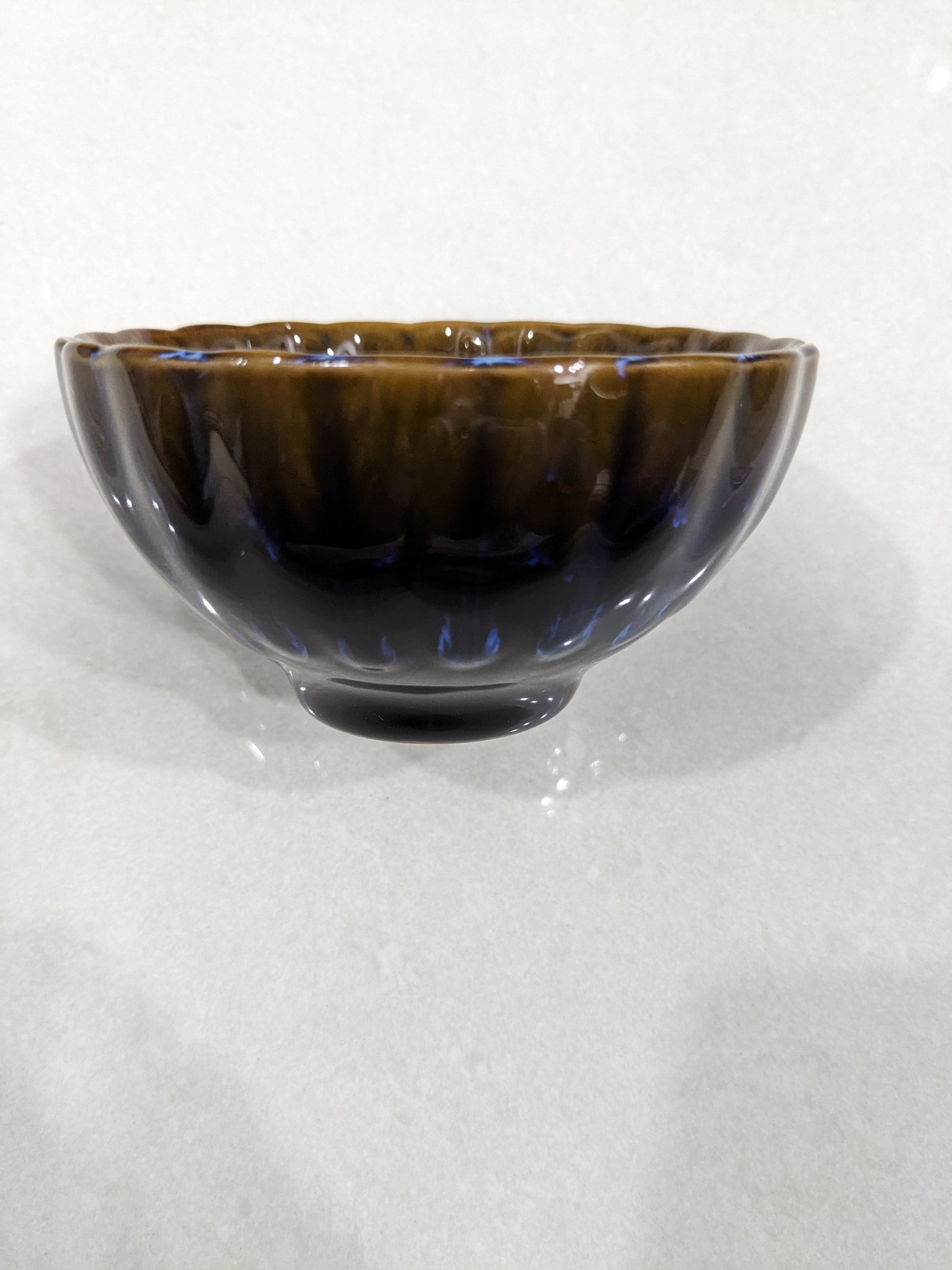 Side profile view of the dark brown and blue glossy glazed vintage ceramic bowl