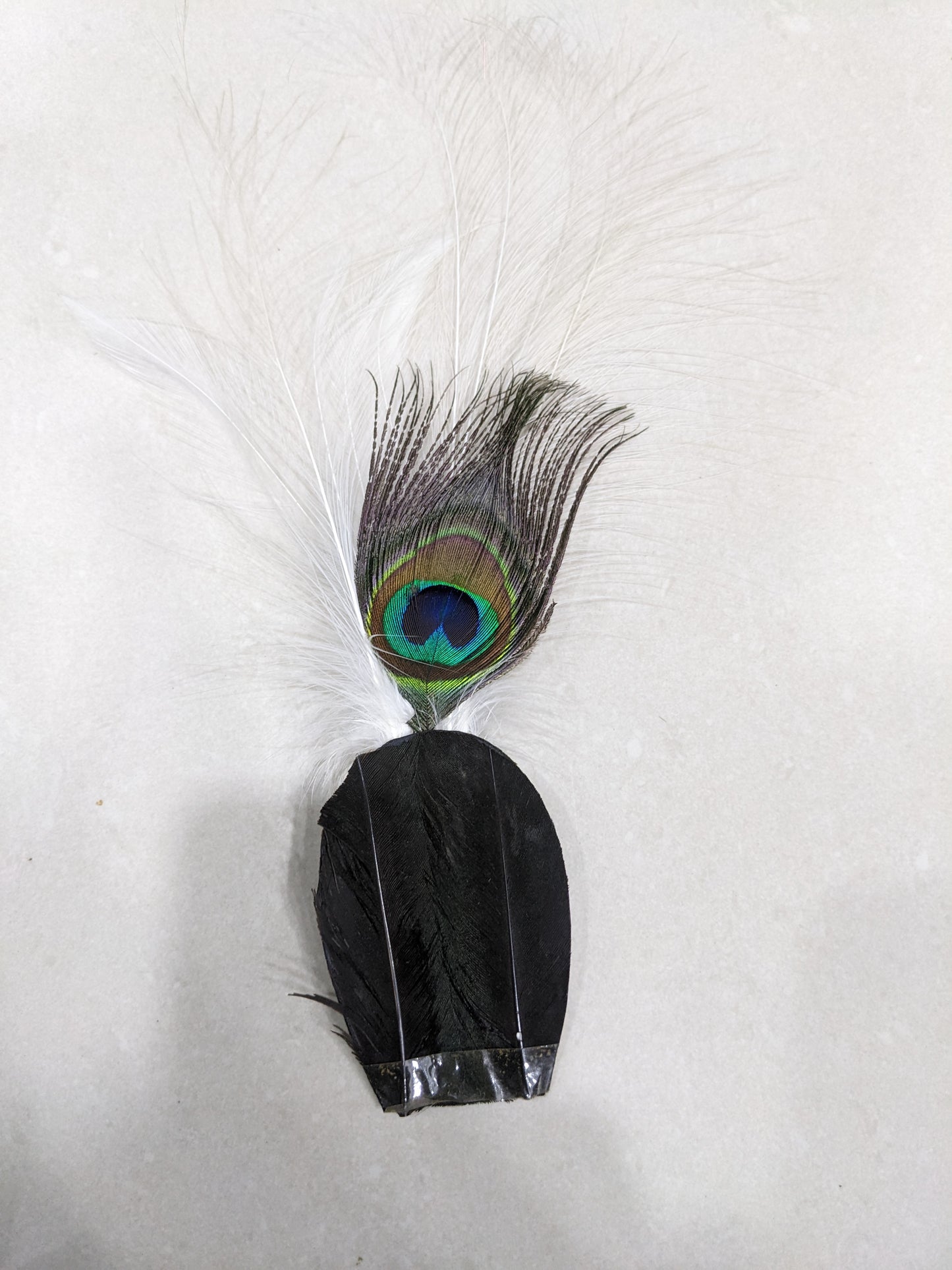 Full view of a vintage hat plume fascinator accessory featuring a natural peacock feather and black base feathers