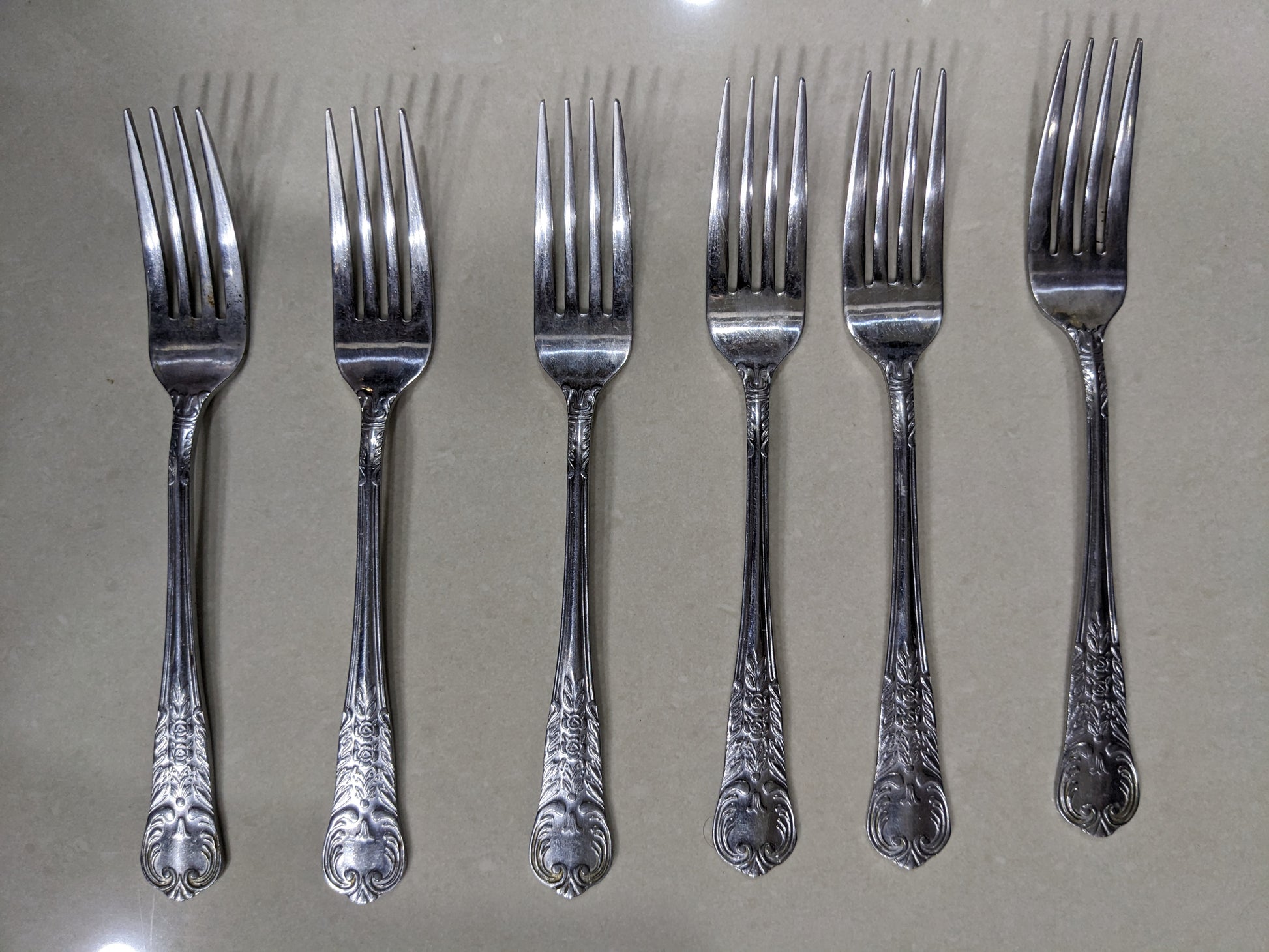 Set of 6 matching vintage silver-plated dinner forks lined up on a clean neutral background